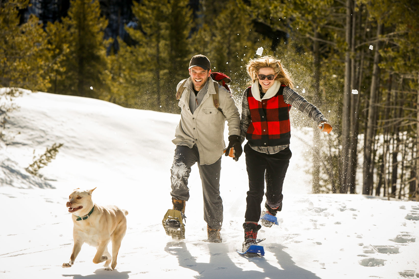 Couple running with snowshoes and dog 